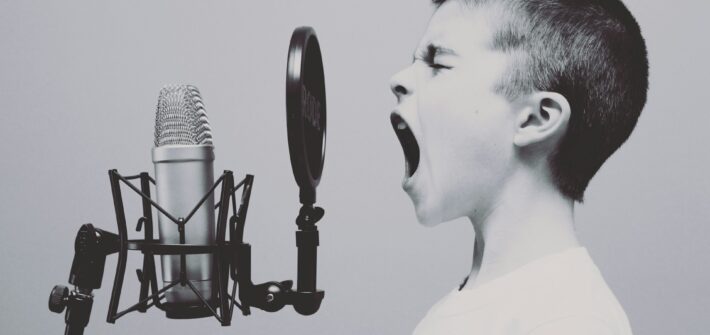 Young singer singing loud in to a microphone