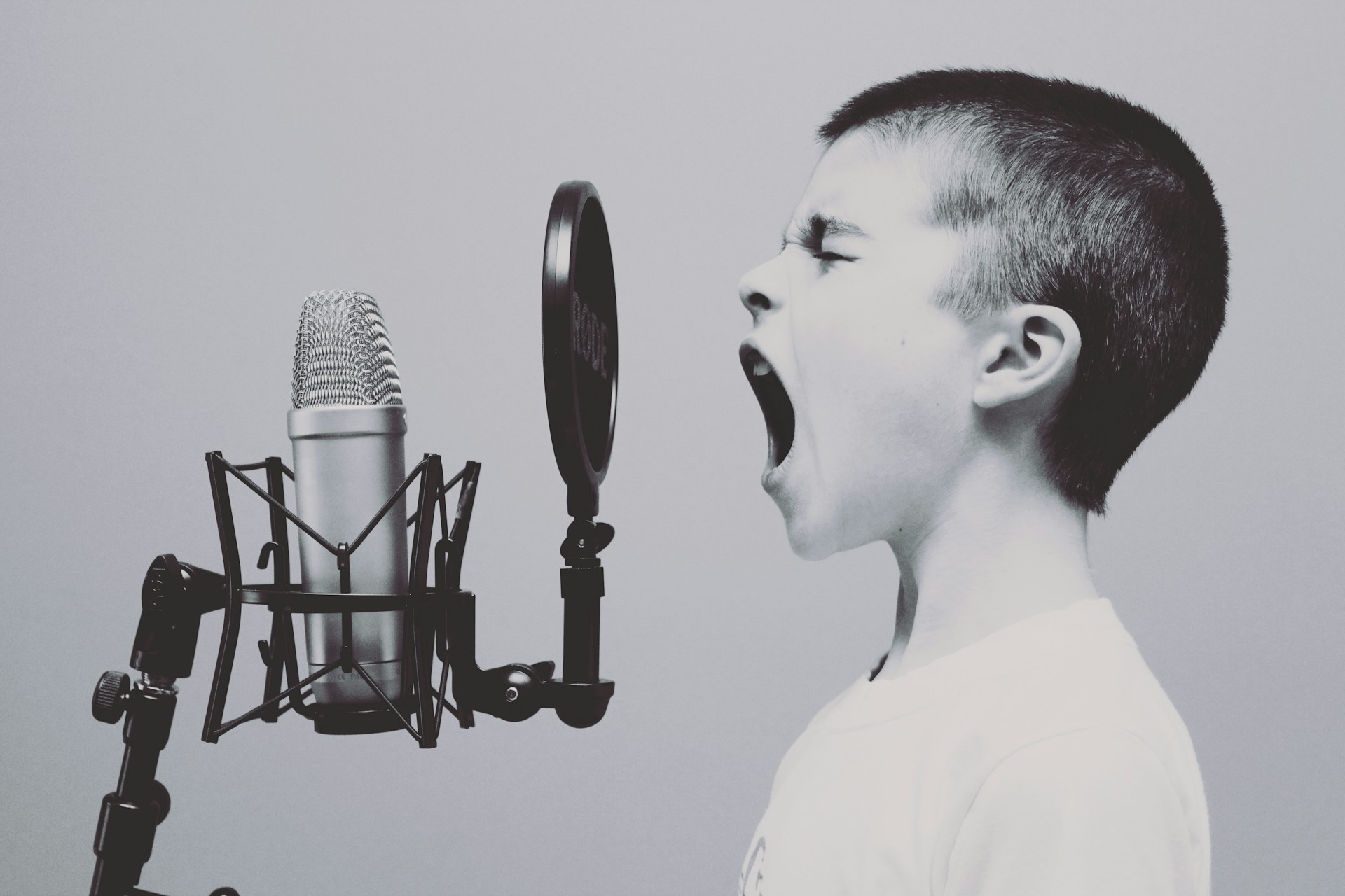 Young singer singing loud in to a microphone