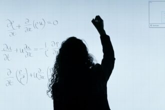 Professor writing partial differential equation on a whiteboard