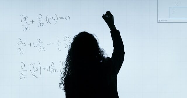 Professor writing partial differential equation on a whiteboard
