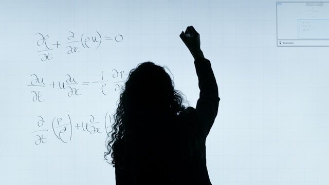 Professor writing partial differential equation on a whiteboard